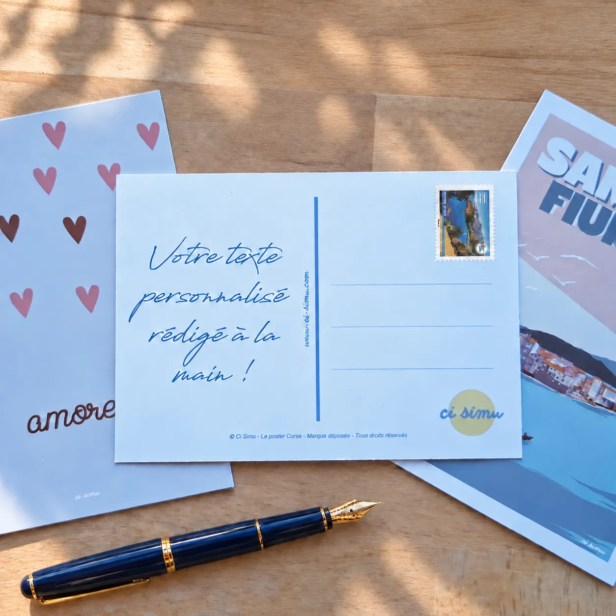 Carte postale personnalisée avec texte manuscrit rédigé à la main, avec timbre et posée avec d'autres cartes illustrées